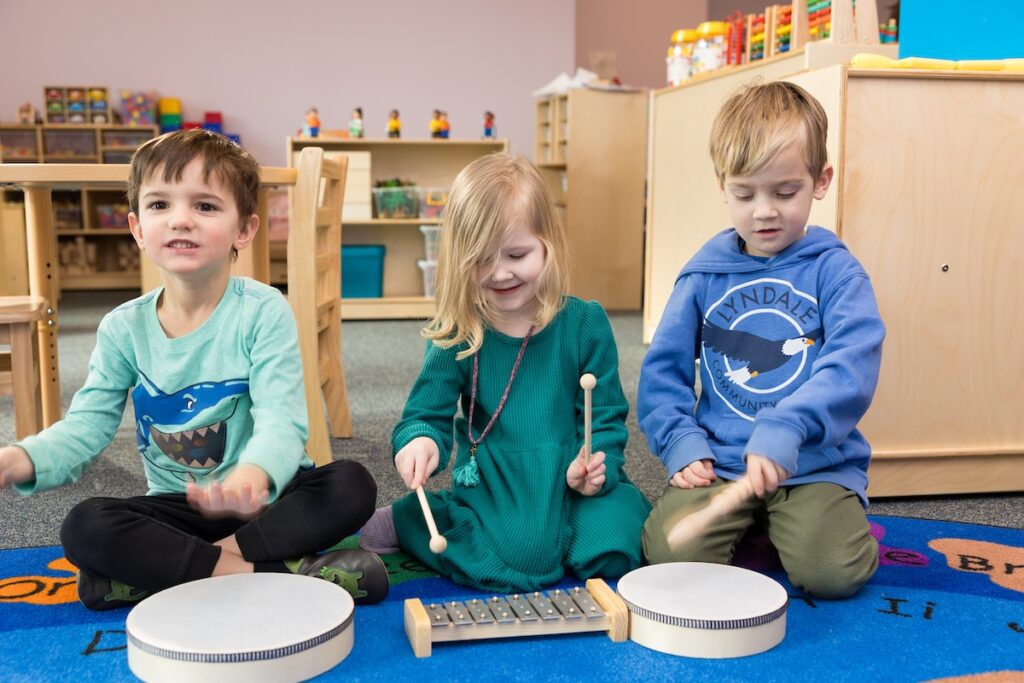 Kids playing with drums and drumsticks at a Tierra Encantada preschool location.
